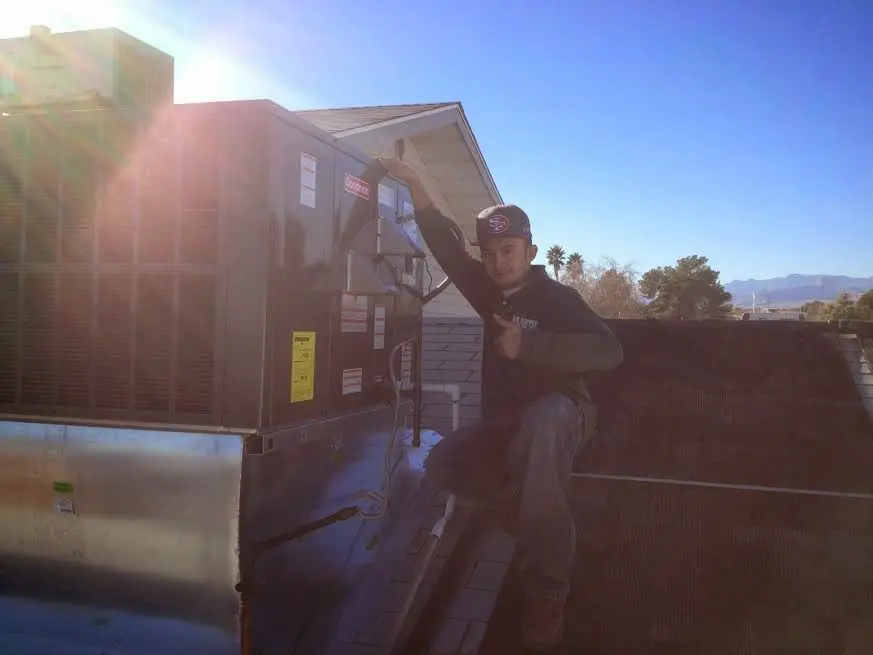 HVAC technician performing Air Duct Cleaning on a rooftop unit in Almena
