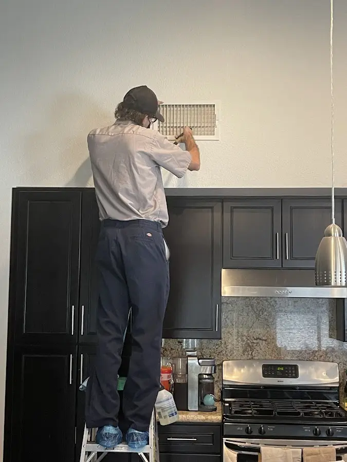 Technician inspecting an air vent during HVAC service in Almena